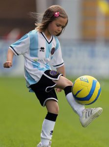 young girl kicking football