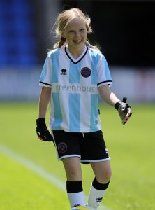 young girl smiling wearing goalkeeper clothes