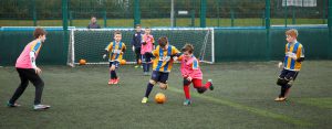 Children play football on artificial grass pitch